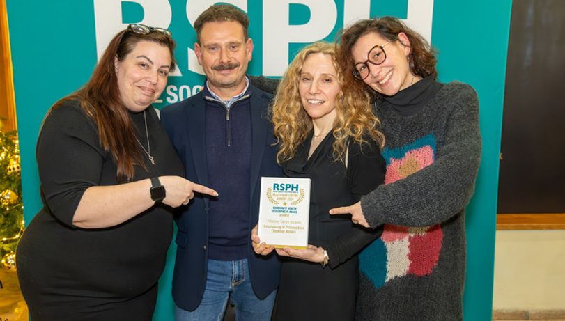 Four winners of a Health & Wellbeing Award pose in front of an RSPH banner