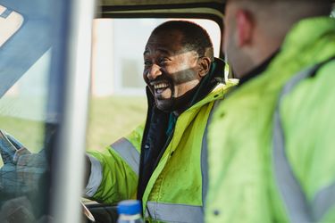 Two workers laughing in their van