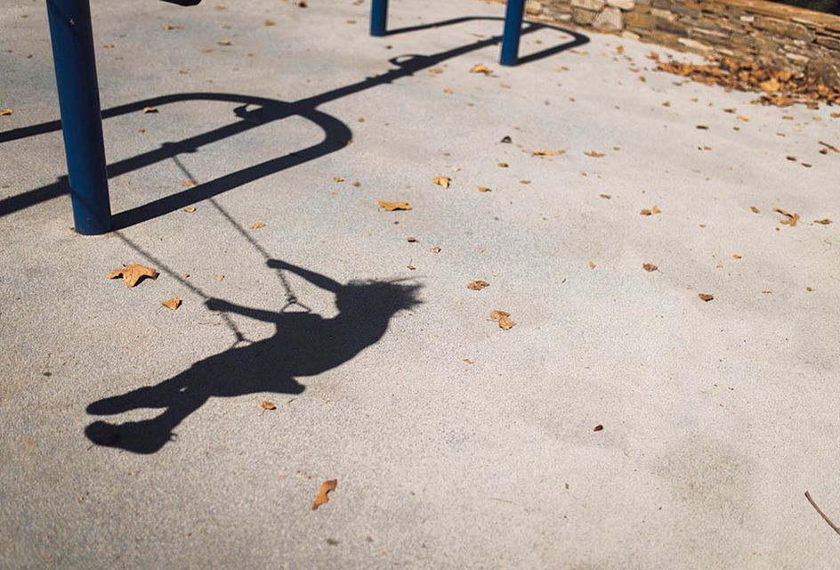 The shadow of a child playing on a swing set