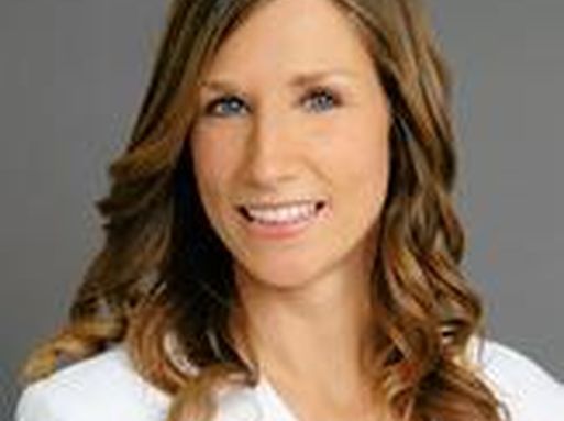 Amy Hucko, a white woman with brown hair and blue eyes wearing a white doctor's coat.